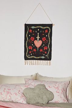 a black wall hanging above a bed with pillows and blankets on top of it in a bedroom