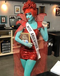 a woman dressed in blue and red is posing for the camera while holding an award