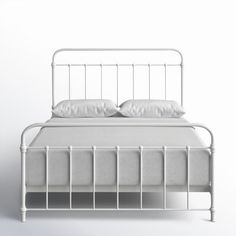 a white metal bed frame with two pillows on the top and bottom, in front of a plain wall