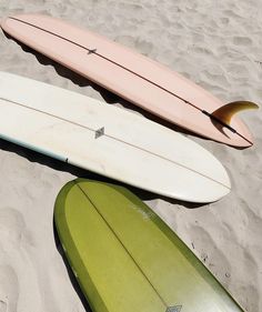 three surfboards laying on the sand at the beach