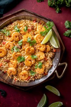 shrimp and rice with cilantro garnish in a pan on a red surface