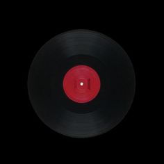 an old black record with red disk in the middle on a black background, taken from above