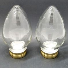 two clear glass vases sitting next to each other on top of a gray surface