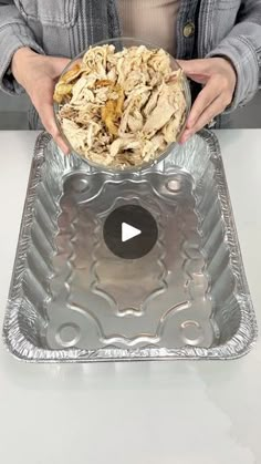 a woman holding a bowl with food in it on top of a metal tray,