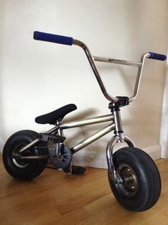 a small metal bike sitting on top of a hard wood floor