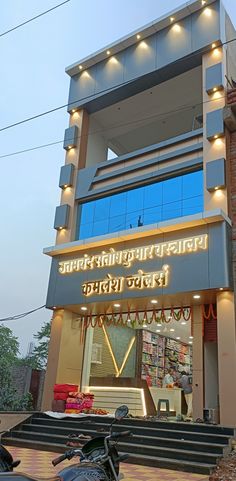 a motorcycle parked in front of a building with lights on it's sides and below the sign