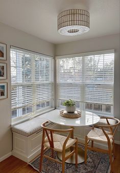 a table with two chairs and a bench in front of the window that has shutters on both sides