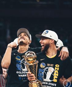 two basketball players are hugging each other with the trophy in front of their heads and hands