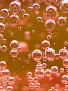 soap bubbles floating on top of each other in a yellow and red liquid filled with water