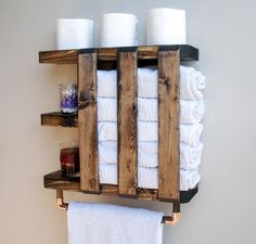 a wooden rack with towels and candles on it in the bathroom, holding several rolls of toilet paper