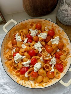 a pan filled with pasta and tomatoes on top of a table