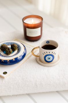 a cup of coffee sitting on top of a table next to a candle