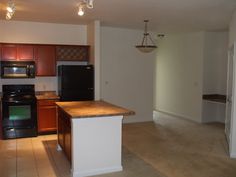 an empty kitchen with black appliances and wood cabinets in it's center island area