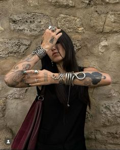 a woman with many tattoos on her arm and arms, holding onto a handbag