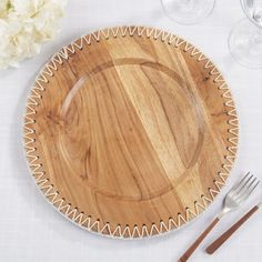 a wooden plate sitting on top of a table next to wine glasses and utensils