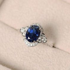 a blue and white diamond ring sitting on top of a cushioned surface in a box