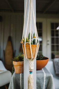 a potted plant hanging from a white pole next to a table covered in plants