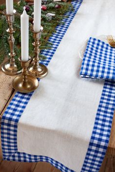 a blue and white checkered table runner on a wooden table next to two candles