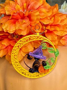 an orange flower and some yellow flowers on top of a table with a circular object in the middle