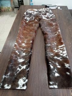 the cow hide is laying on top of a wooden table with white and brown spots