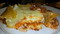 a white plate topped with lasagna covered in cheese