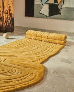 a yellow rug is on the floor next to a painting