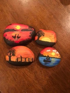 four painted rocks sitting on top of a wooden table