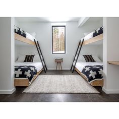 two bunk beds in a room with white walls and wood flooring, along with a rug on the floor