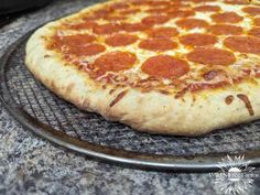 a pepperoni pizza sitting on top of a metal rack next to an oven door