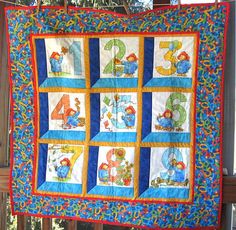 a quilt hanging from a clothes line with numbers and animals painted on the fabric in it