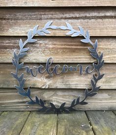 a metal wreath with the word welcome hanging from it's side on a wooden deck