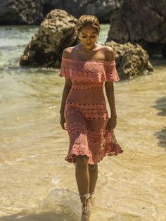 a woman in a pink dress walking into the water