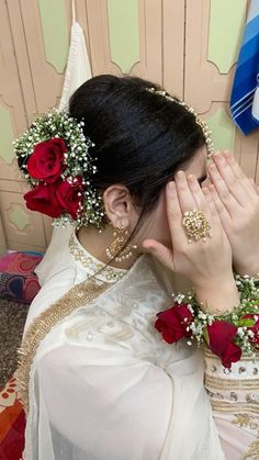 a woman with flowers in her hair covering her eyes and holding her hands to her face