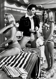 three women in bathing suits are standing next to a man