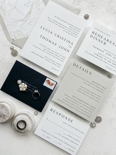 the wedding stationery is laid out on top of each other, including two rings