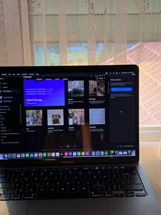 an open laptop computer sitting on top of a white table next to a window with curtains