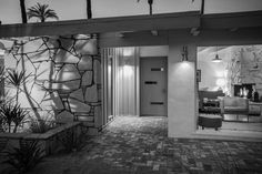 a black and white photo of the inside of a house with palm trees in the background