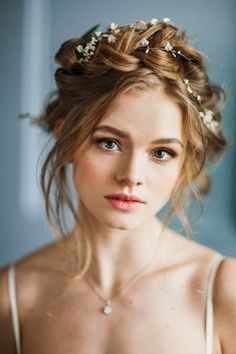 a young woman wearing a wedding dress with flowers in her hair is looking at the camera