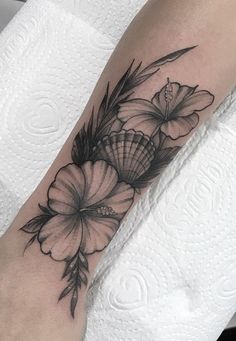 a black and white flower tattoo on the left arm, with an insect in it