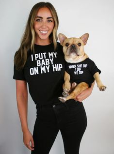 a woman holding a dog wearing a shirt that says i put my baby on my hip