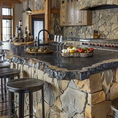 a kitchen with stone counter tops and bar stools next to an island in the middle