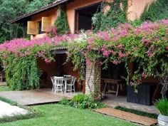 a house with pink flowers growing on it's walls and wooden decking area