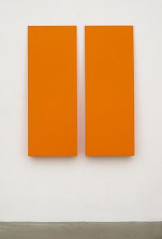 two orange pieces of art on a white wall