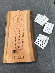 a wooden board game with four playing cards and dices on the floor next to it