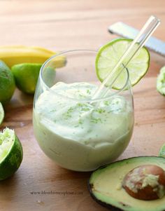 an avocado dip in a glass with limes around it