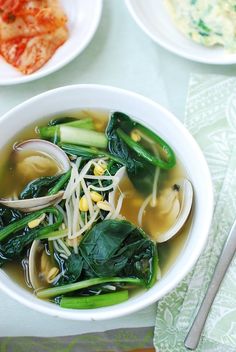 a white bowl filled with soup and veggies on top of a green table cloth