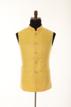 The yellow brocade Nehru jacket for men is a stylish and elegant piece of clothing that exudes class and sophistication. The jacket is made from high-quality brocade fabric that has a unique texture and sheen, which adds to its overall appeal. The Nehru jacket has a mandarin collar that gives it a distinct look and makes it stand out from other jackets. The collar is raised and has a slightly rounded edge, which gives it a modern twist. The jacket is sleeveless, which makes it ideal for warmer weather and can be worn over a shirt or a kurta. The yellow color of the brocade fabric is bright and vibrant, making it perfect for a summer or spring wedding or any formal occasion. The jacket has a tailored fit that is designed to flatter the wearer's body shape and create a sharp, refined look. O Yellow Formal Kurta For Festive Occasions, Yellow Formal Traditional Kurta, Festive Gold Nehru Jacket For Winter, Traditional Gold Bandhgala For Semi-formal Occasions, Gold Nehru Jacket For Festive Semi-formal Occasions, Gold Fitted Nehru Jacket For Ceremonial Occasions, Fitted Gold Nehru Jacket For Festivals, Gold Fitted Nehru Jacket For Festivals, Yellow Fitted Bandhgala For Wedding