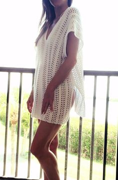 a woman is standing on a balcony with her legs crossed and wearing white clothing, smiling at the camera