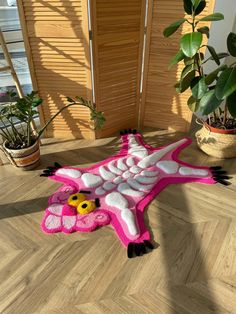 a pink dragon rug sitting on top of a wooden floor next to a potted plant