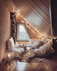 an attic bedroom with string lights and pillows on the floor, along with a window